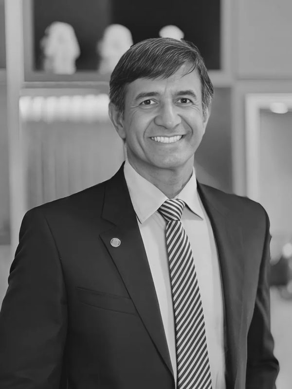 Fabio Brongar, de terno escuro e gravata listrada, sorrindo, em foto em preto e branco